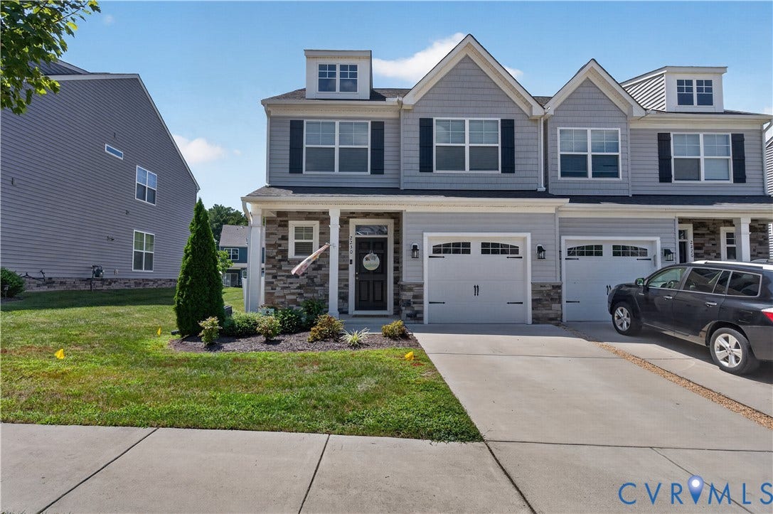2230 Nightfall Drive, Chesterfield, VA 23236 Multi-story townhome exterior featuring gray horizontal siding, stone veneer accents, double gables, dual carriage-style garage doors, and front dormer windows
