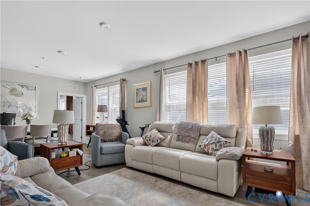 3900 Maze Runner Drive, #102, Chesterfield, VA 23112 Open-concept living space featuring wood-finish flooring and expansive windows with horizontal blinds