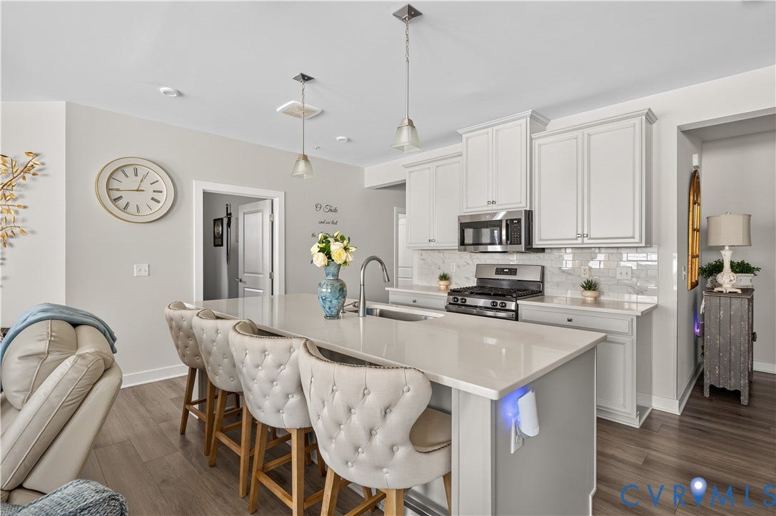 3900 Maze Runner Drive, #102, Chesterfield, VA 23112 Kitchen featuring a center island with quartz countertop and undermount sink, shaker-style cabinetry, stainless steel appliances, subway tile backsplash, and wood-finish flooring