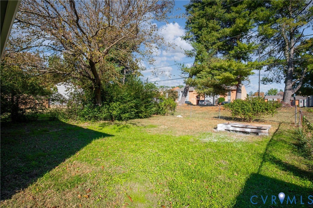 5429 Blueridge Avenue, Fulton, Richmond, VA 23231 Open backyard featuring a grassy lawn, mature trees, and chain-link perimeter fencing