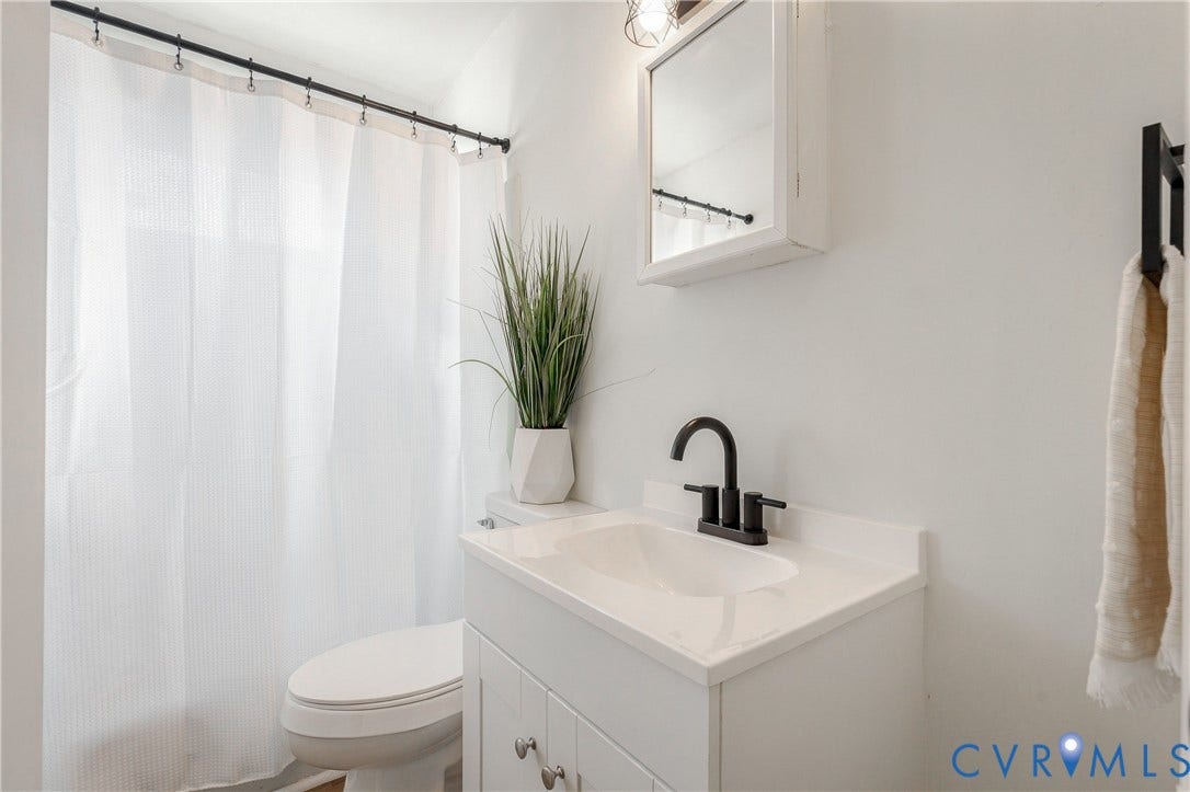 5429 Blueridge Avenue, Fulton, Richmond, VA 23231 White vanity with an integrated basin, matte black faucet, mirrored medicine cabinet, and shower curtain with a black rod