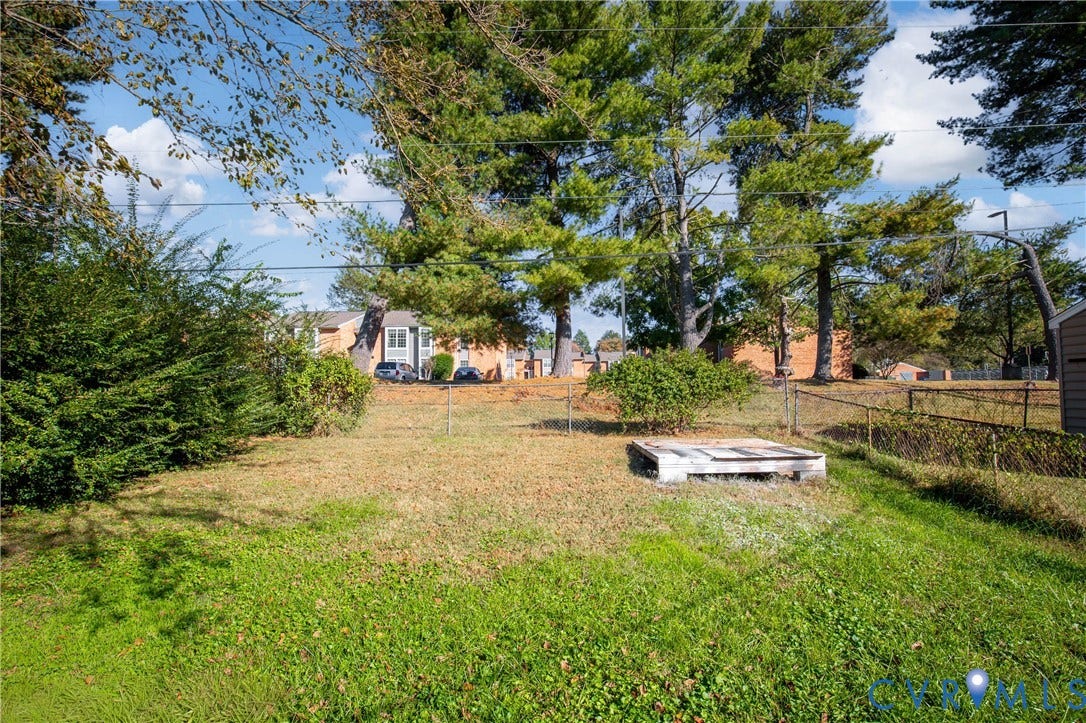 5429 Blueridge Avenue, Fulton, Richmond, VA 23231 Backyard area featuring mature trees, perimeter chain-link fencing, and a concrete pad