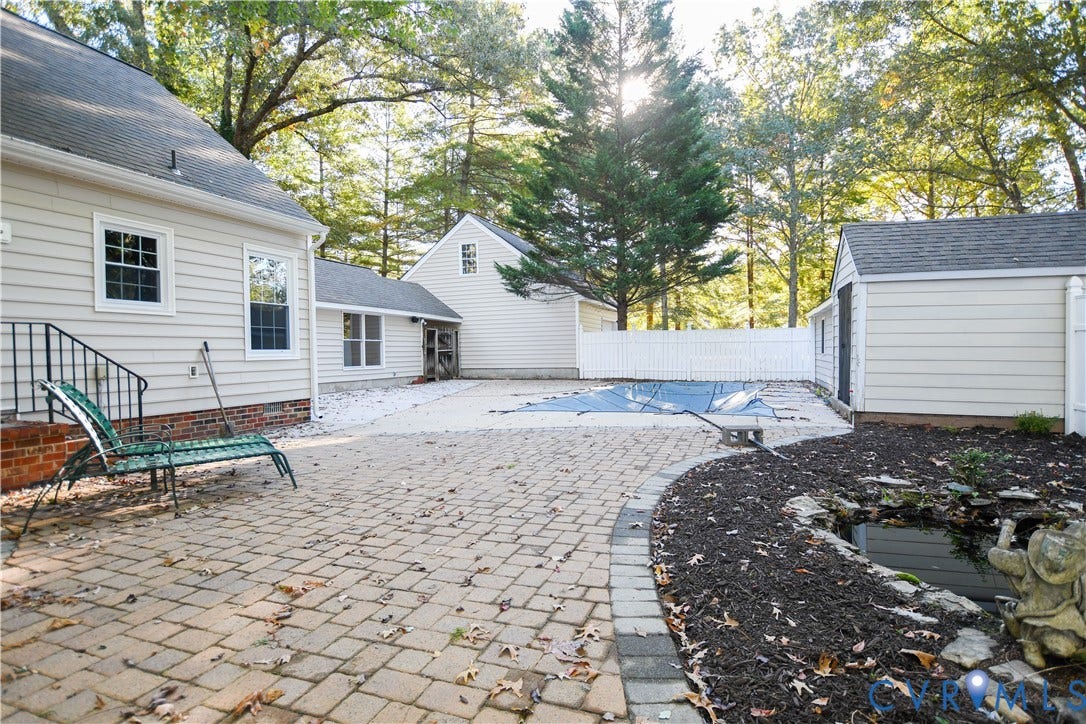 3486 Venter Road, Minors Pines, Aylett, VA 23009 Rear exterior featuring a brick-paver patio, swimming pool with cover, detached outbuilding, and stone-lined garden pond
