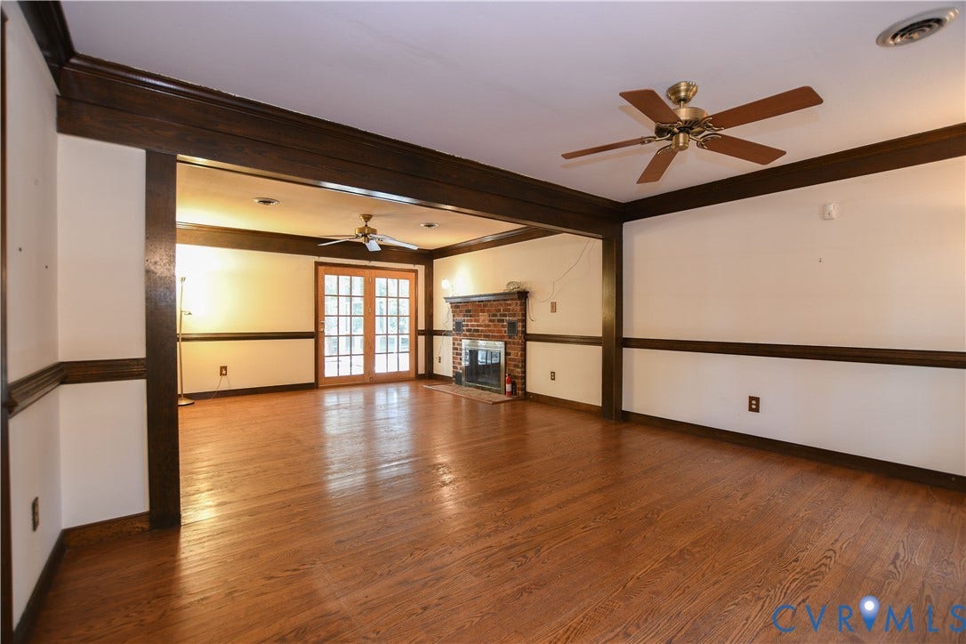 3486 Venter Road, Minors Pines, Aylett, VA 23009 Spacious interior featuring wood-finish flooring, dark wood-tone crown molding and chair rail, brick fireplace, and French-style glass doors