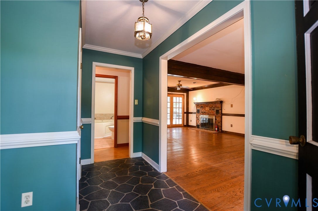 3486 Venter Road, Minors Pines, Aylett, VA 23009 Foyer featuring flagstone flooring, chair rail molding, and a pendant light fixture, with hardwood flooring and a brick fireplace visible in the interior space
