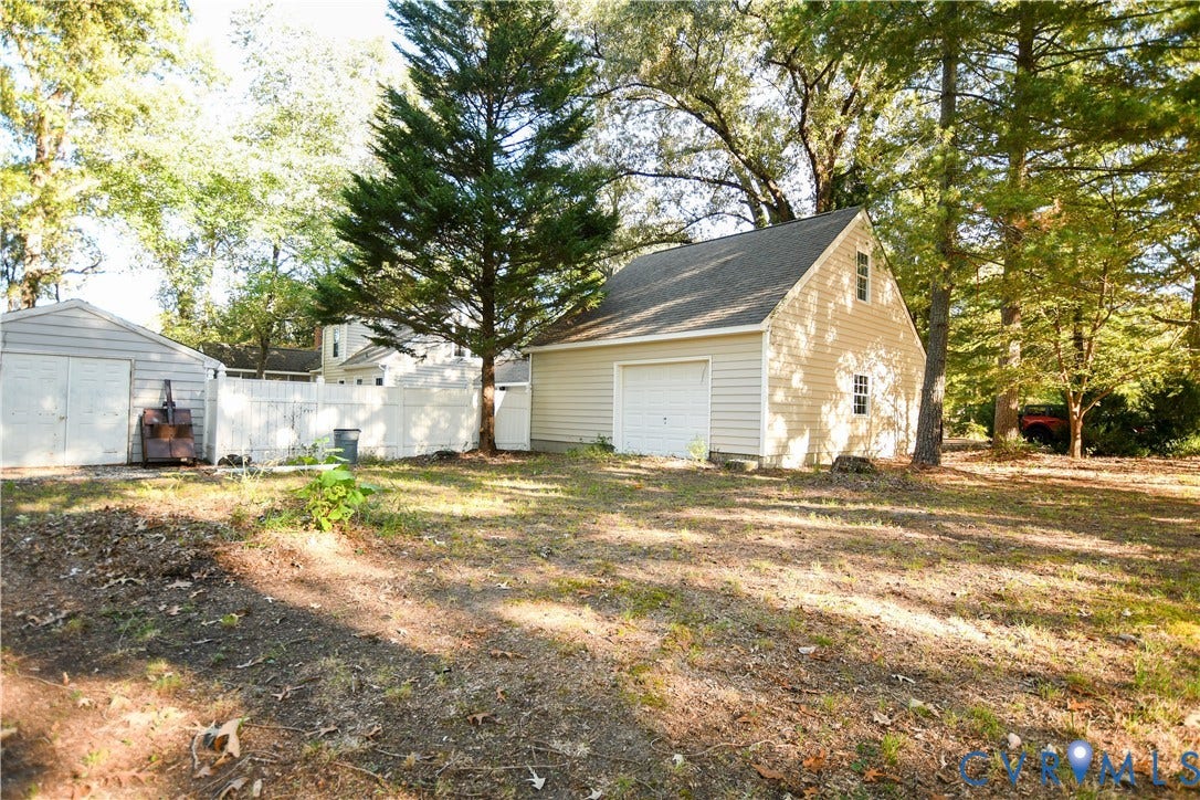 3486 Venter Road, Minors Pines, Aylett, VA 23009 Detached multi-level garage with lap siding, asphalt shingle roof, and white sectional garage door, accompanied by an auxiliary storage structure and perimeter white vinyl fencing