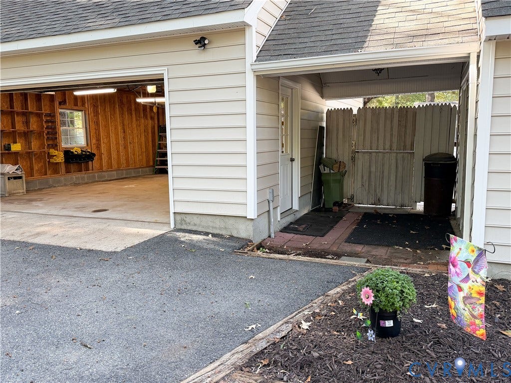 3486 Venter Road, Minors Pines, Aylett, VA 23009 Exterior featuring horizontal vinyl siding, multi-car garage with built-in wall shelving, covered side entry, and enclosed side yard with privacy fencing