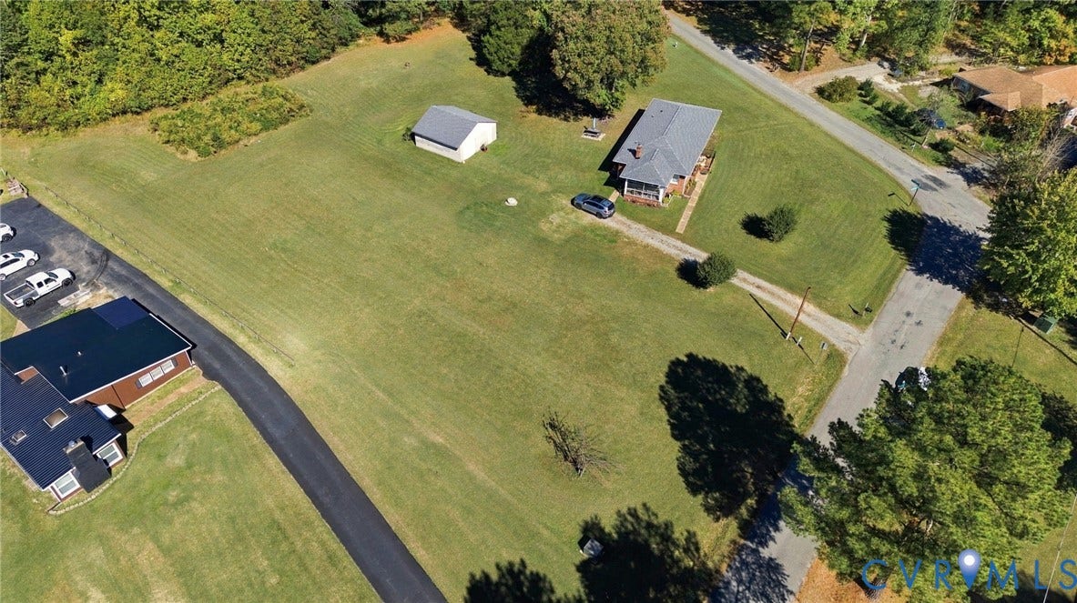 Expansive lot featuring a detached storage structure, long gravel driveway, and mature landscaping
