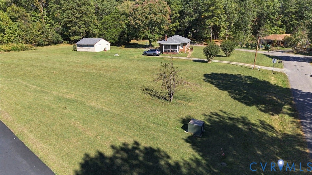 Expansive lawn, detached storage structure, and mature trees situated on a parcel with road frontage