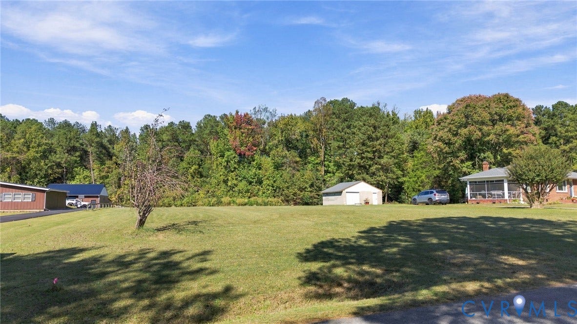 Expansive property grounds featuring a sprawling lawn, detached garage, mature trees, and a screen-enclosed porch