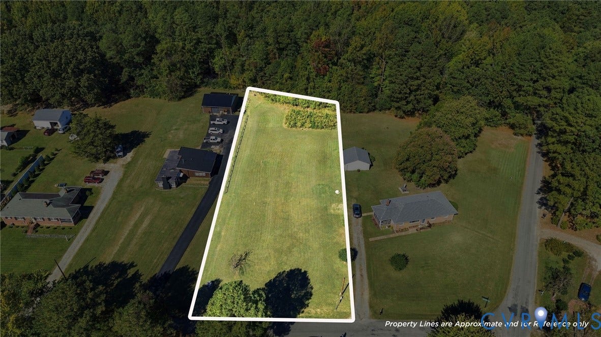 Expansive parcel of land featuring open grassy terrain, mature tree borders, and direct road access