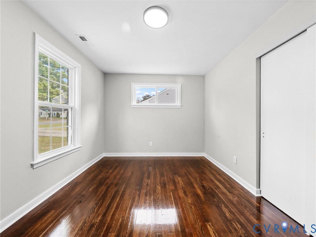 1811 Murdoch Road, Henrico, VA 23229 Room featuring polished wood-finish flooring, neutral wall paint, a double-hung window, a slider window, and a built-in closet with sliding doors