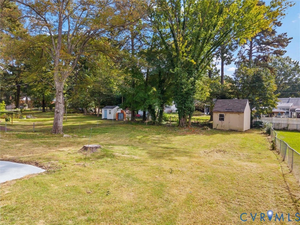 1811 Murdoch Road, Henrico, VA 23229 Expansive backyard featuring mature trees, a fenced perimeter, and two detached storage structures