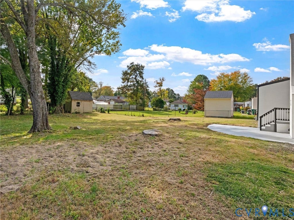 1811 Murdoch Road, Henrico, VA 23229 Expansive backyard featuring a concrete patio, detached storage structures, and mature trees