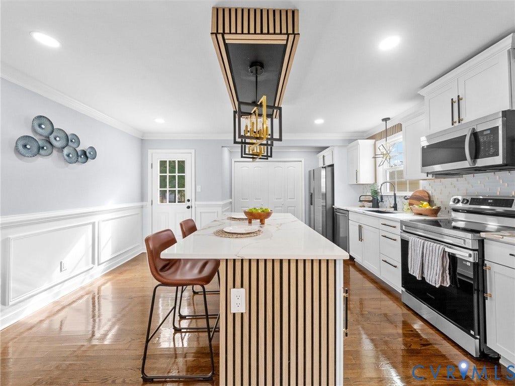 1811 Murdoch Road, Henrico, VA 23229 Kitchen featuring a center island with slatted wood detailing and a stone-style countertop, custom vertical-slat pendant lighting, shaker-style cabinetry, stainless steel appliances, and wainscoting