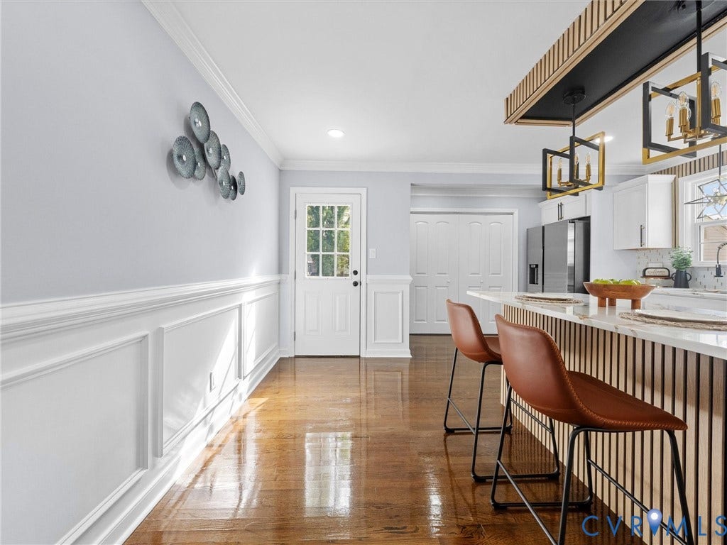 1811 Murdoch Road, Henrico, VA 23229 Wood-finish flooring, wainscoting, a kitchen island with vertical wood-slat detailing, stone-finish countertops, and geometric pendant lighting