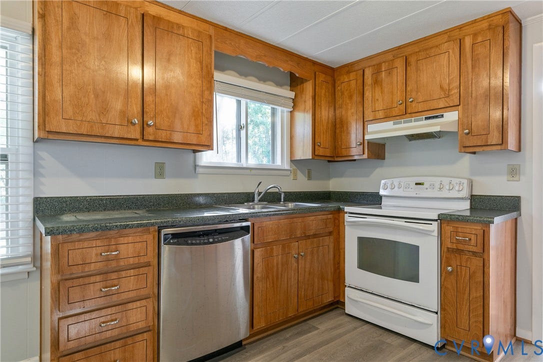 20311 McKenney Highway, Dinwiddie, VA 23882 Kitchen featuring wood cabinetry, solid-surface countertops, a stainless steel dishwasher, a freestanding range, and wood-finish flooring