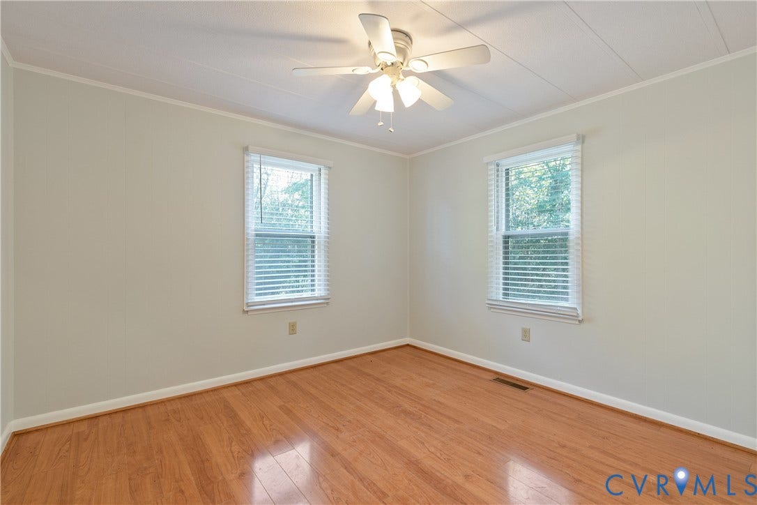 20311 McKenney Highway, Dinwiddie, VA 23882 Room featuring wood-finish flooring, two windows with horizontal blinds, and a central ceiling fan with integrated lighting