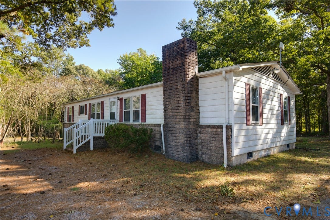 20311 McKenney Highway, Dinwiddie, VA 23882 Exterior featuring white siding, a brick masonry chimney, decorative window shutters, and an elevated wooden entry deck