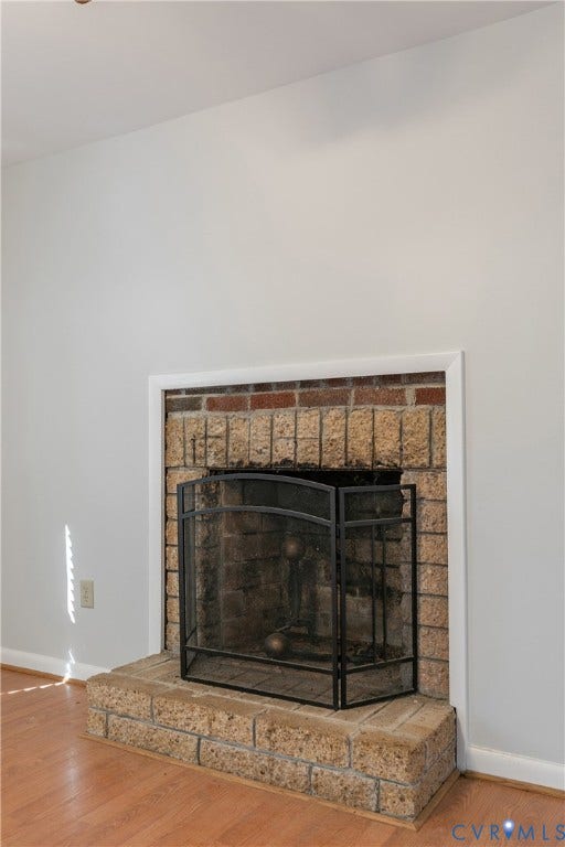 20311 McKenney Highway, Dinwiddie, VA 23882 Fireplace featuring a textured stone facade, elevated stone hearth, and white trim molding set against wood-finish flooring