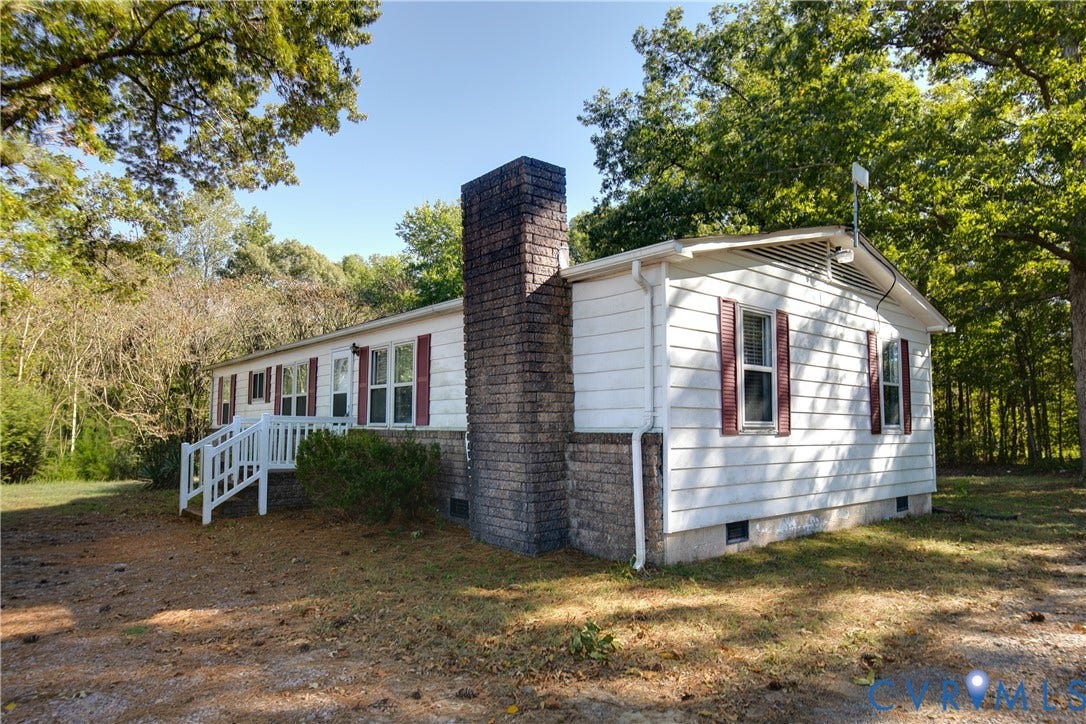 20311 McKenney Highway, Dinwiddie, VA 23882 White siding exterior featuring decorative shutters, a prominent brick chimney, and a raised wooden entrance deck