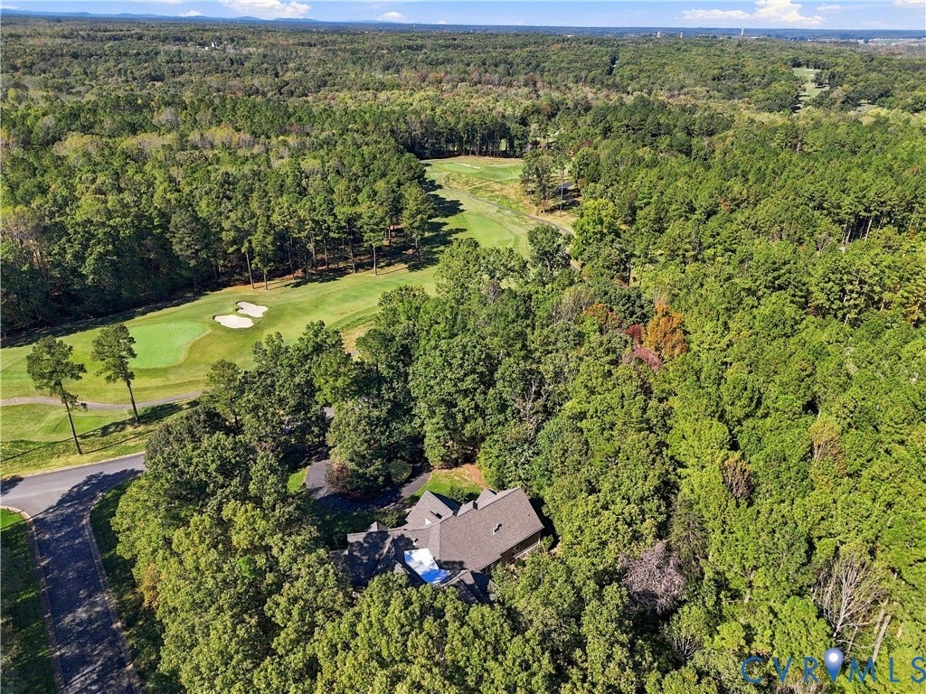 3056 Greywalls Drive, Powhatan, VA 23139 Aerial perspective featuring a multi-gabled roofline, asphalt driveway, dense mature tree canopy, and direct proximity to a golf course fairway