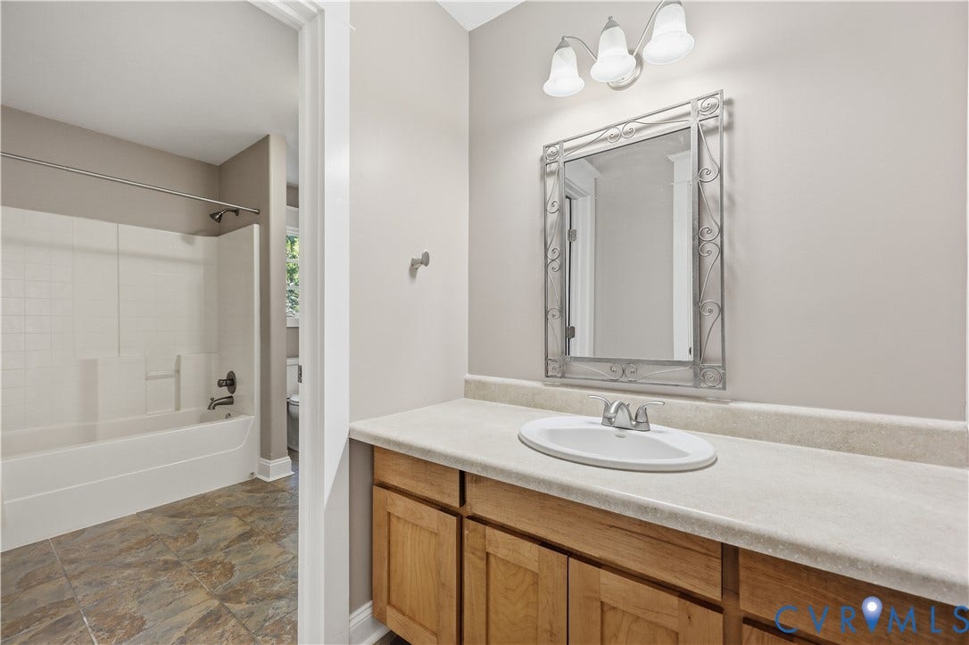 3056 Greywalls Drive, Powhatan, VA 23139 Upstairs Bathroom featuring a wood-finish vanity with a stone-composite countertop, integrated sink, three-light fixture, and tub-shower combination with tiled flooring