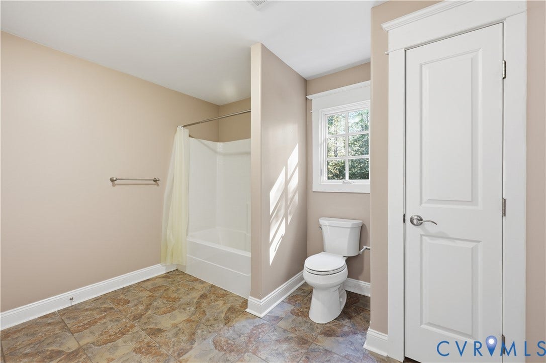 3056 Greywalls Drive, Powhatan, VA 23139 Upstairs Bathroom featuring a white porcelain toilet, a shower-tub combination with a wall-mounted rod, multi-pane window, and patterned stone-finish tile flooring