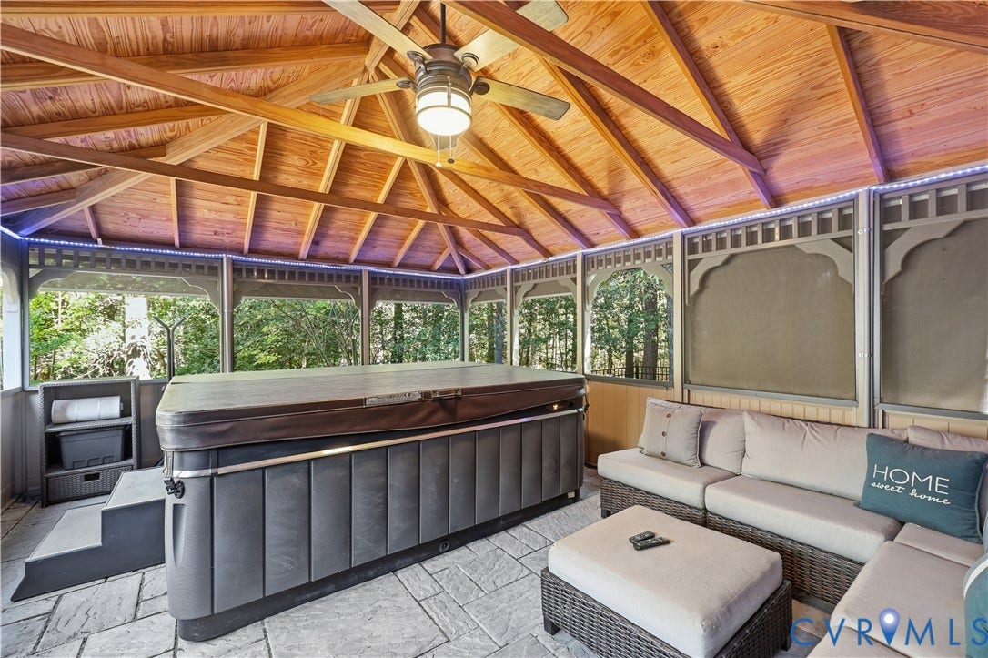 3056 Greywalls Drive, Powhatan, VA 23139 Screened enclosure featuring a wood-plank vaulted ceiling, exposed timber rafters, stone-finish flooring, and a central ceiling fan with integrated lighting