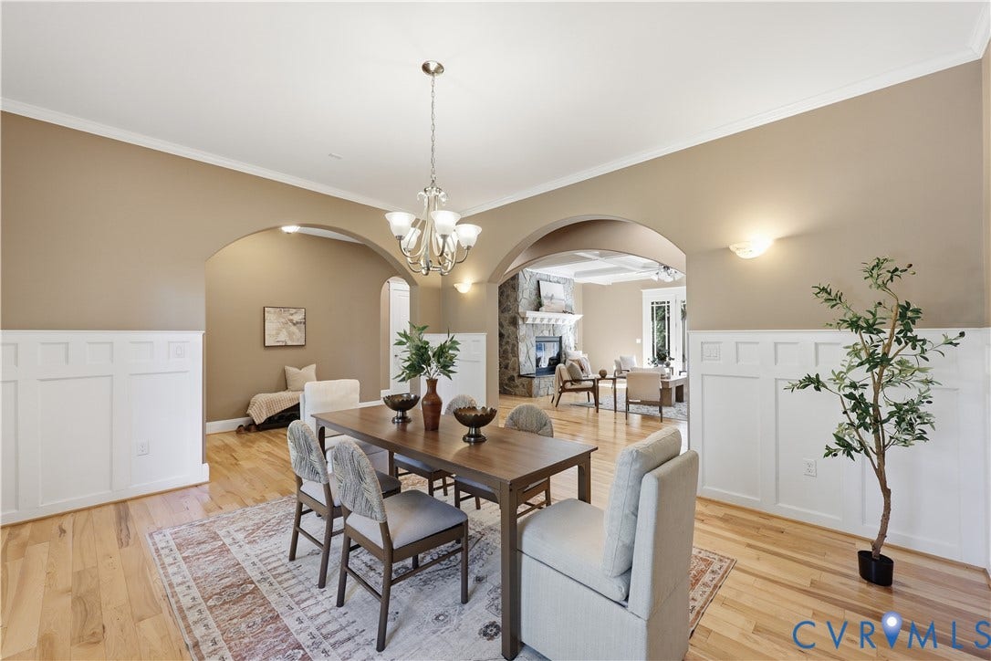 3056 Greywalls Drive, Powhatan, VA 23139 Dining area featuring wood-finish flooring, white wainscoting, arched architectural openings, and a tiered chandelier