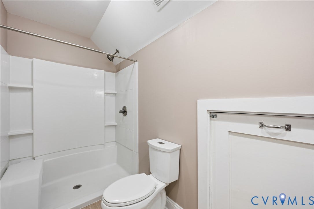 3056 Greywalls Drive, Powhatan, VA 23139 Upstairs Full bathroom featuring a white tub-shower enclosure with integrated shelving, a dual-flush toilet, and white paneled access cabinetry with a polished metal handle