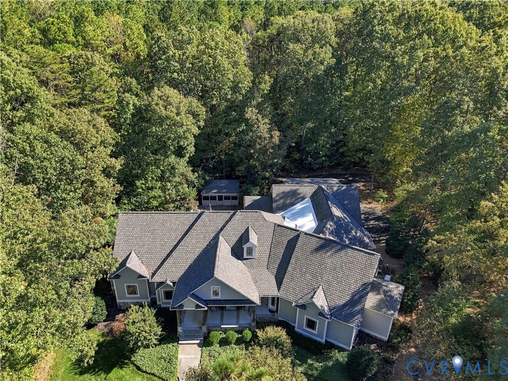 3056 Greywalls Drive, Powhatan, VA 23139 Aerial perspective of a multi-gabled residence featuring shake-style roof shingles, horizontal siding, a covered entryway, and an independent screened structure, all situated on a wooded lot
