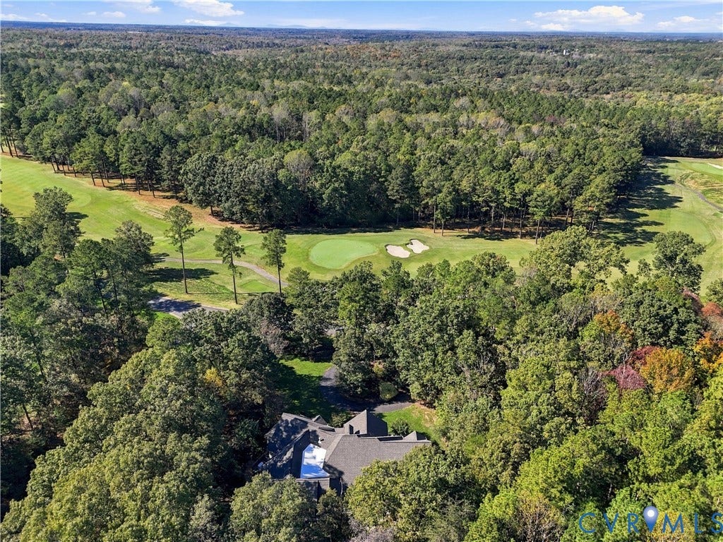 3056 Greywalls Drive, Powhatan, VA 23139 Aerial perspective showcasing a residential property bordered by mature woodlands and a golf course featuring sand bunkers and manicured turf