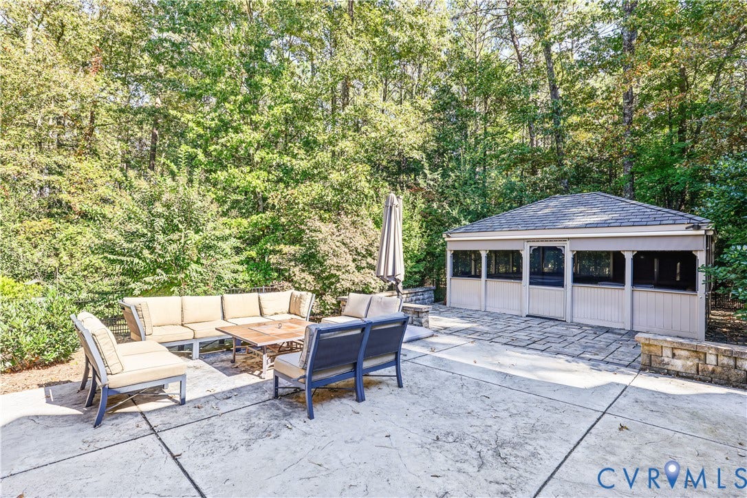 3056 Greywalls Drive, Powhatan, VA 23139 Stamped concrete patio featuring a detached screened pavilion, stacked stone retaining wall, and mature wooded perimeter