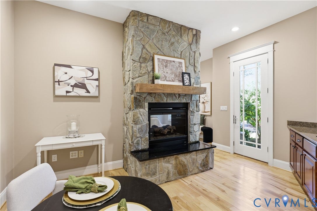 3056 Greywalls Drive, Powhatan, VA 23139 Floor-to-ceiling stone fireplace featuring a dark stone hearth and natural wood mantel, wood-finish flooring, and a glass-paneled exterior door with white trim
