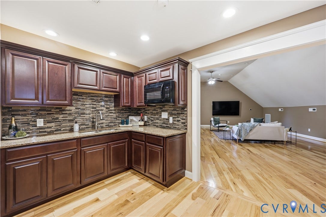 3056 Greywalls Drive, Powhatan, VA 23139 Kitchen featuring dark stained cabinetry, stone-finish countertops, tile backsplash, built-in microwave, and wood-finish flooring