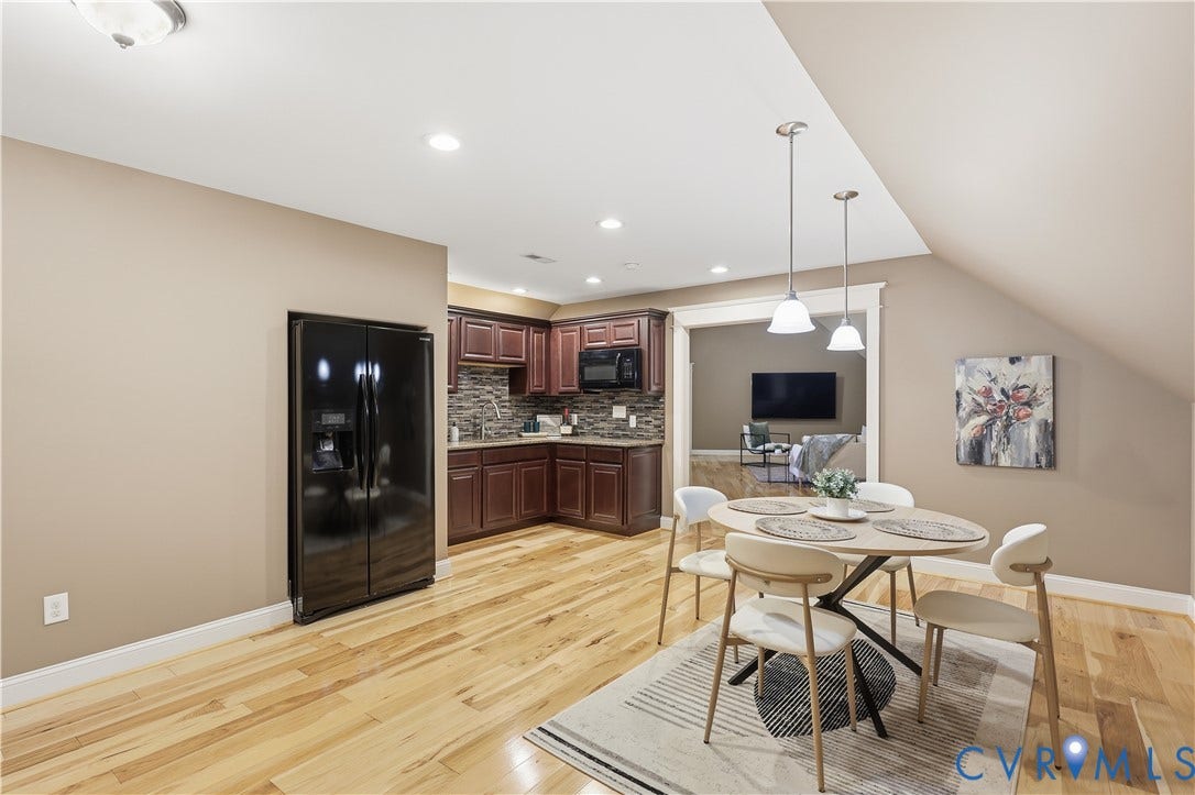 3056 Greywalls Drive, Powhatan, VA 23139 Kitchen featuring dark-finish cabinetry, stone-tiled backsplash, built-in black refrigerator, wood-finish flooring, and dual pendant lighting