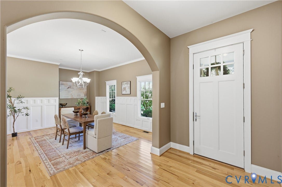 3056 Greywalls Drive, Powhatan, VA 23139 Archway entryway featuring wood-finish flooring, white wainscoting, and a multi-pane glass door with millwork casing