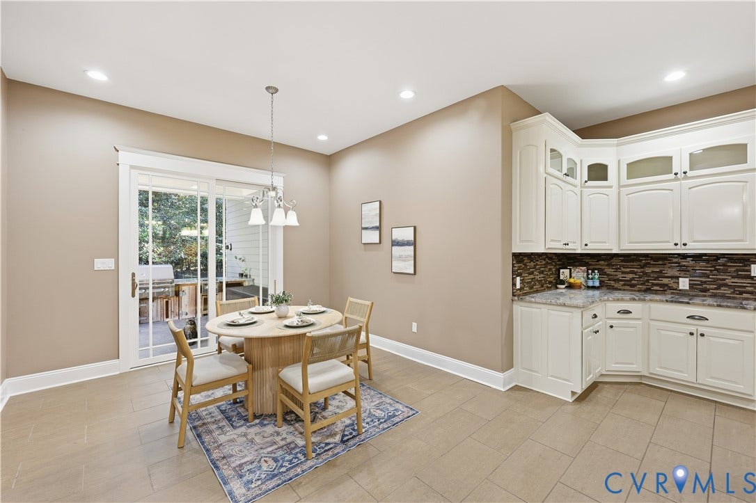 3056 Greywalls Drive, Powhatan, VA 23139 White shaker-style cabinetry, multi-tone stone tile backsplash, stone-finish countertops, tile flooring, and glass-pane sliding doors