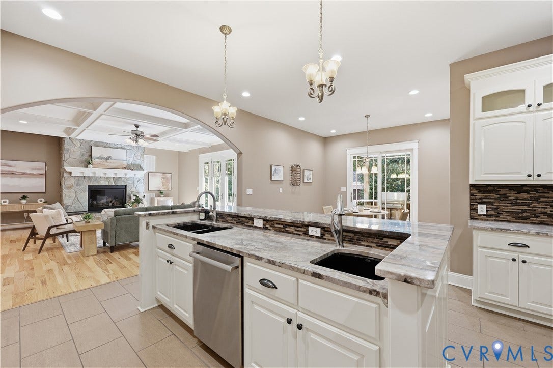 3056 Greywalls Drive, Powhatan, VA 23139 Kitchen featuring stone countertops, white cabinetry, a dual-basin sink with a gooseneck faucet, and recessed lighting, with a coffered ceiling and stone fireplace visible in the background