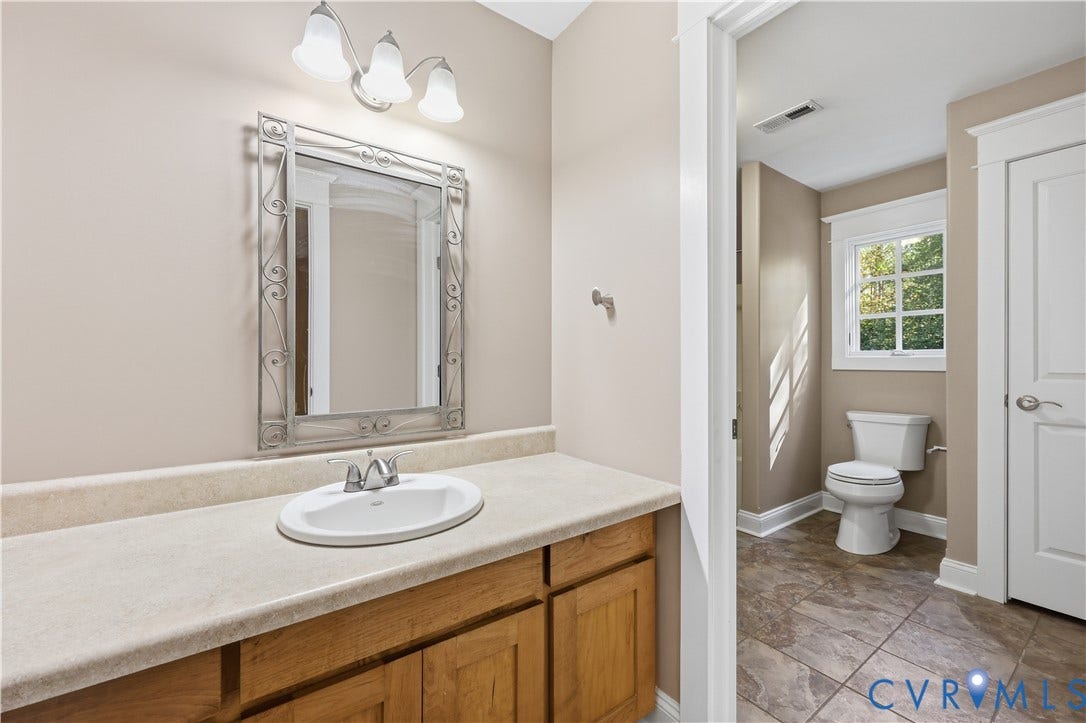 3056 Greywalls Drive, Powhatan, VA 23139 Upstairs Bathroom featuring an oak vanity with a stone-finish countertop, integrated oval sink, decorative metal-framed mirror, and ceramic tile flooring