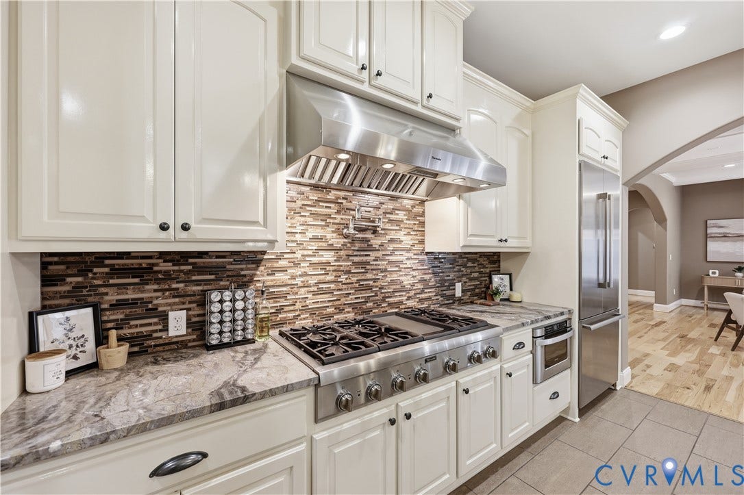 3056 Greywalls Drive, Powhatan, VA 23139 Kitchen featuring white cabinetry, stone countertops, multi-toned tile backsplash, stainless steel gas range with overhead vent hood, and stainless steel refrigerator