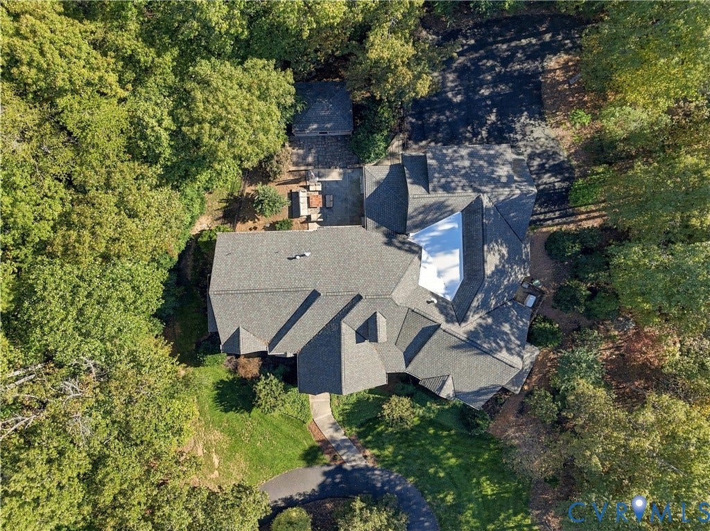 3056 Greywalls Drive, Powhatan, VA 23139 Aerial perspective of a multi-gabled architectural roofline, paved driveway, concrete hardscaping, and mature woodland canopy on a private lot