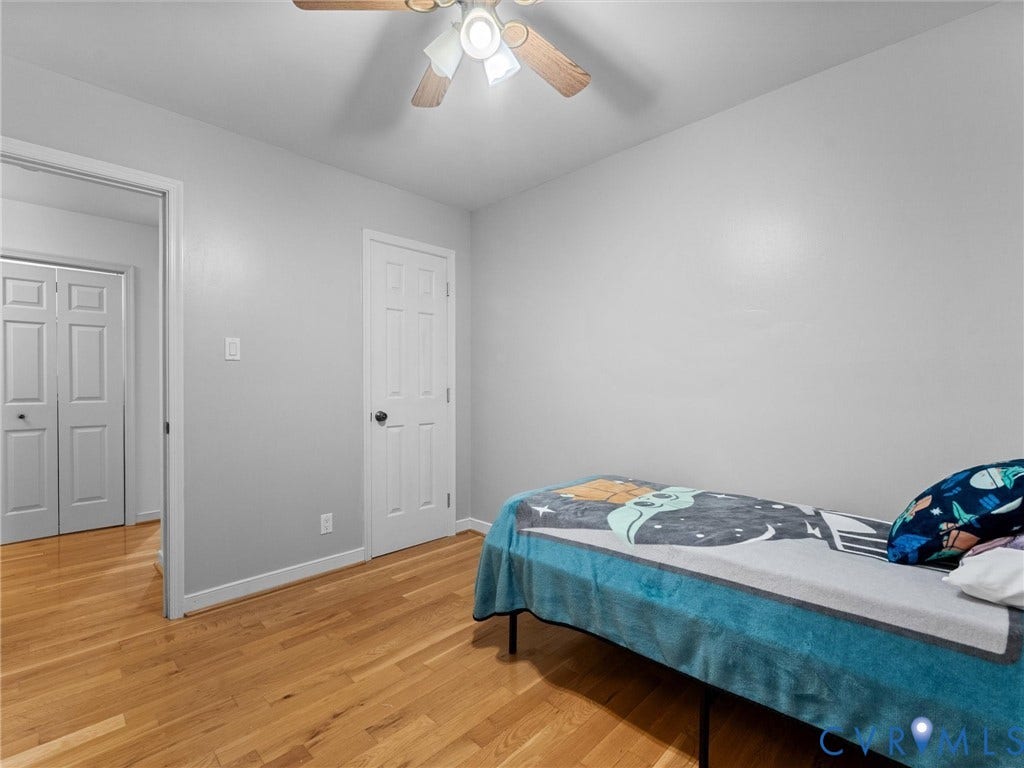 Interior space featuring wood-finish flooring, a ceiling fan with integrated lighting, and six-panel interior doors