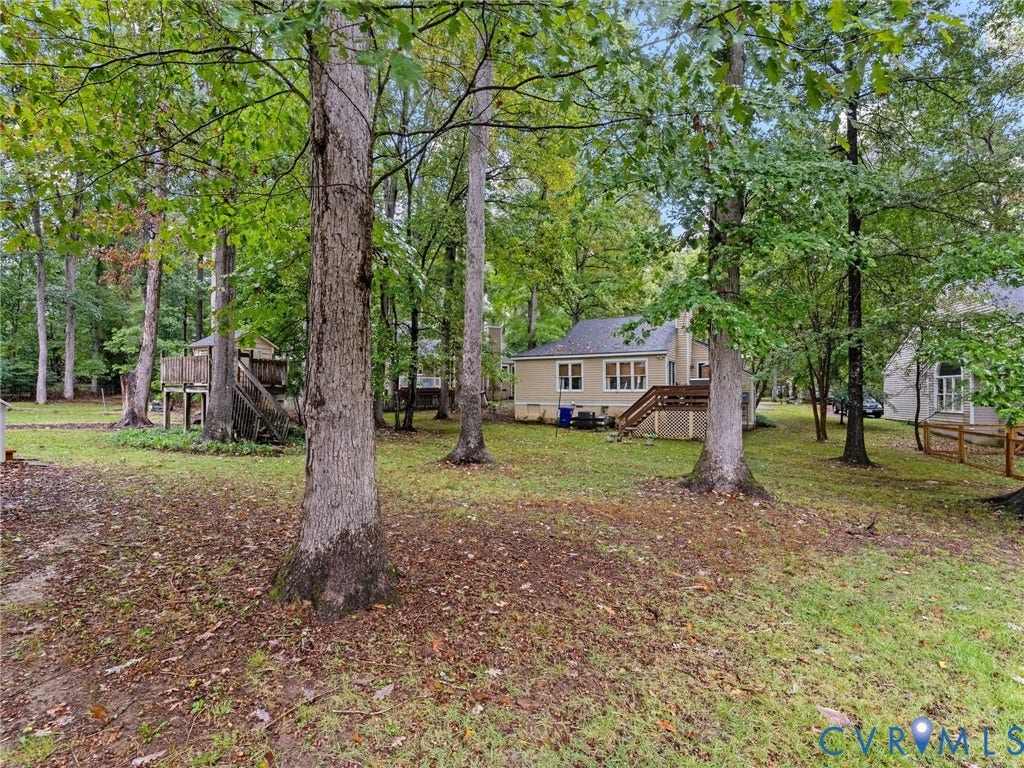 Expansive backyard featuring mature trees, an elevated wooden deck, and a detached wooden structure
