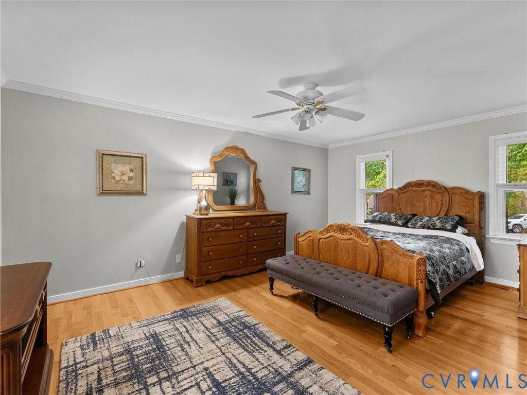 Neutral-toned interior featuring wood-finish flooring, crown molding, and a central ceiling fan with integrated lighting
