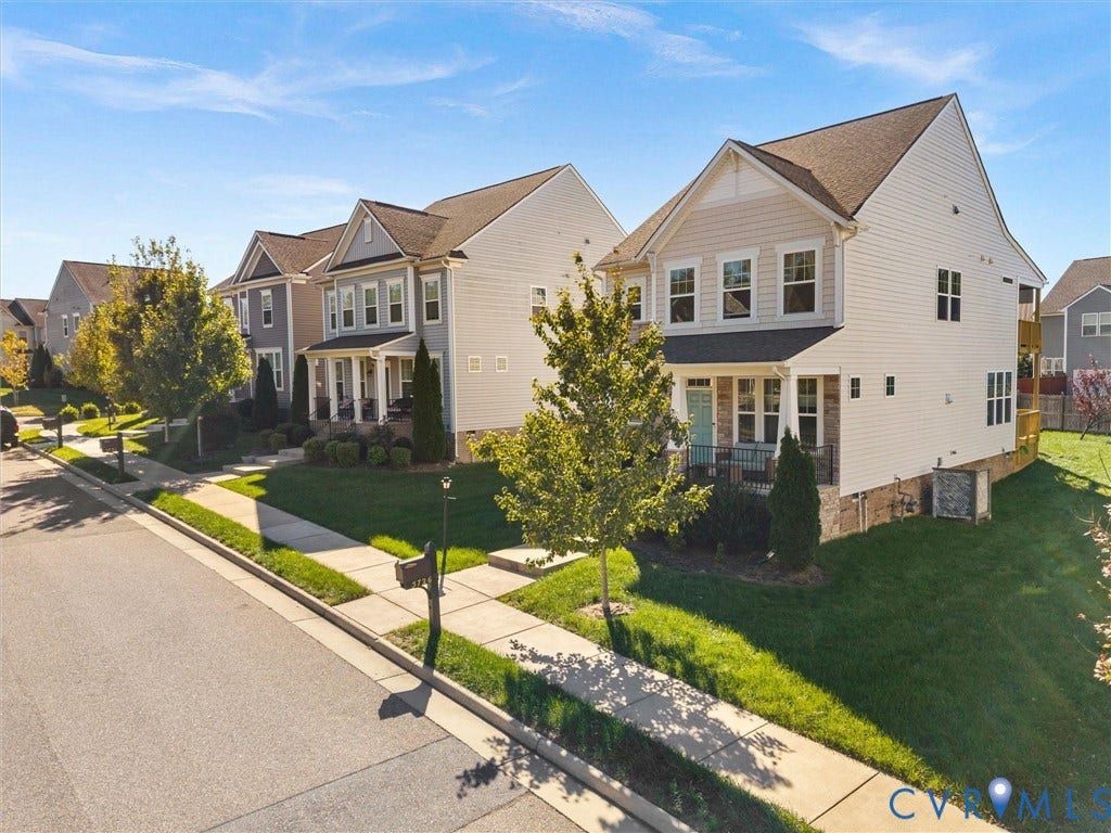 5726 Gossamer Place, Wynwood At FoxCreek, Moseley, VA 23120 Two-story residence featuring light-toned vinyl siding, stone masonry accents, a covered front porch, and a dedicated concrete driveway
