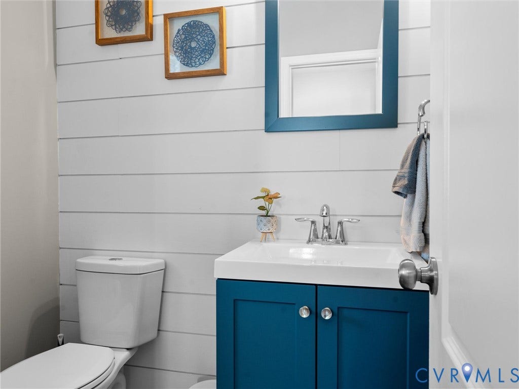 5726 Gossamer Place, Wynwood At FoxCreek, Moseley, VA 23120 Bathroom featuring horizontal shiplap wall paneling, a blue vanity cabinet with a white basin, a polished chrome centerset faucet, and a matching framed wall mirror