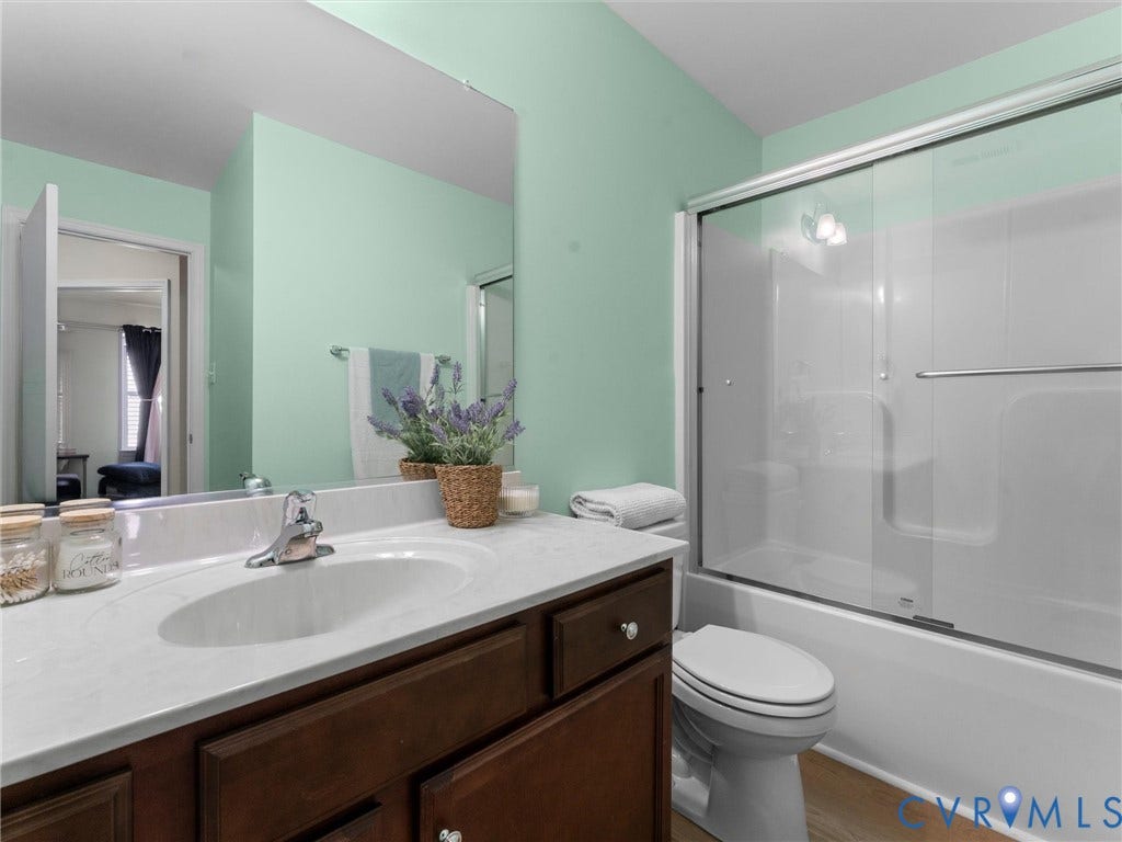 5726 Gossamer Place, Wynwood At FoxCreek, Moseley, VA 23120 Bathroom featuring a vanity with a light-toned countertop, integrated oval sink, chrome-finish faucet, and a glass-enclosed tub-shower combination