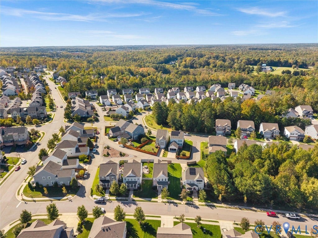 5726 Gossamer Place, Wynwood At FoxCreek, Moseley, VA 23120 Aerial perspective of a residential community featuring multi-story dwellings, paved roadways, sidewalk infrastructure, and extensive forested canopy
